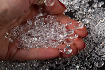 Beautiful transparent crystal on the female palm. Woman holding diamonds. Cropped Hand Holding...