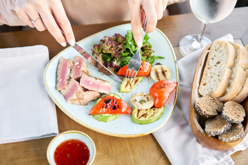Woman eat Medium rare tuna with lettuce and hot sauce. Lunch in a cafe. Restaurant menu