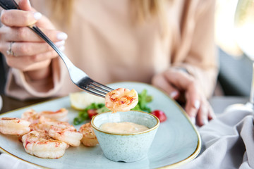 Grilled Argentine shrimp with mango-jalapeno sauce. Lunch in a restaurant, a woman eats delicious and healthy food. Delicious fresh seafood prawns with fresh vegetables and lime. Cream sauce