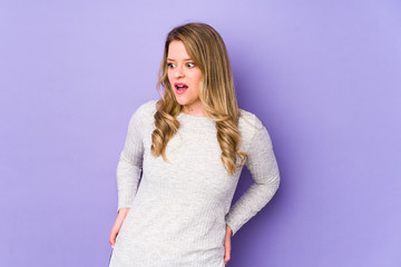 Young caucasian woman isolated on purple background being shocked because of something she has seen.
