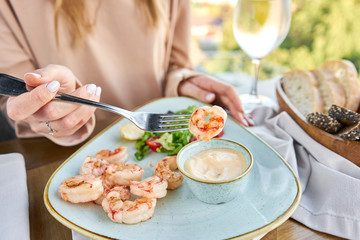Grilled Argentine shrimp with mango-jalapeno sauce. Lunch in a restaurant, a woman eats delicious and healthy food. Delicious fresh seafood prawns with fresh vegetables and lime. Cream sauce