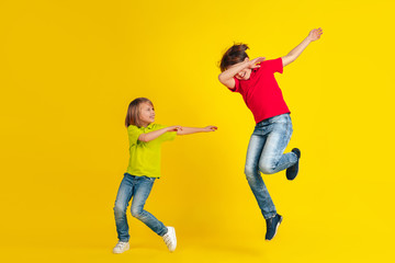 Fototapeta na wymiar Winner. Happy children playing and having fun together on yellow studio background. Caucasian kids in bright clothes looks playful, laughting, smiling. Concept of education, childhood, emotions.