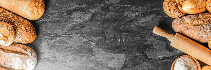 Bread with wheat and bowl of flour on dark board, White bakery food concept panorama or wide banner photo.