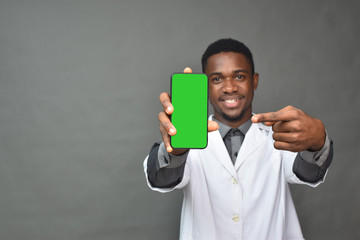 young black man in medical field, wearing a white coat showing his phone screen and points to it