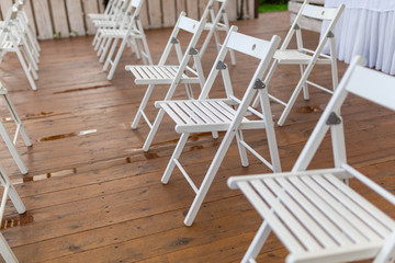 Rows of white chairs in rows on the beach sand. Conference or outdoor wedding. Watching a movie or a street theater.