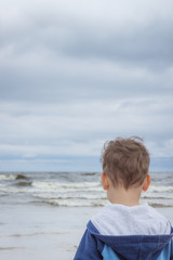 Fototapeta na wymiar The little boy looks at the rough sea waves