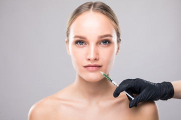 Portrait of young woman getting cosmetic injection. Closeup of beautiful woman gets injection in her face. Filler injections. Lip augmentation. Beautiful perfect lips