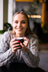 Portrait of beautiful mature woman drinking a cup of tea in cafeteria. Happy woman in a cafe drinking coffee and looking at camera. Portrait of smiling lady relaxing in a coffee shop.
