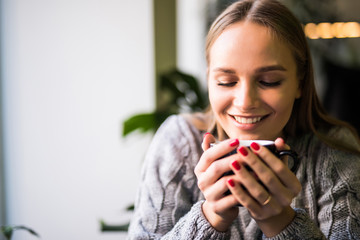 Portrait of beautiful mature woman drinking a cup of tea in cafeteria. Happy woman in a cafe drinking coffee and looking at camera. Portrait of smiling lady relaxing in a coffee shop.