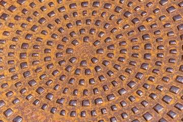 Close-up of a metal, rusty, round manhole with polished elements. Abstract background texture.