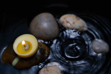 burning candle over water with rocks