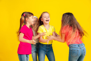 Happiness. Happy children playing and having fun together on yellow studio background. Caucasian kids in bright clothes looks playful, laughting, smiling. Concept of education, childhood, emotions.