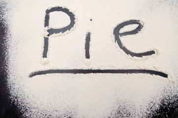 word Pie is written on a black background with the flour. Inscription.