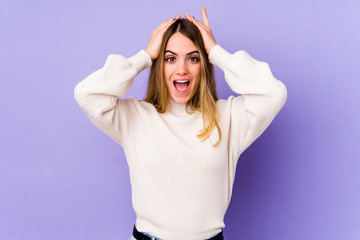 Young caucasian woman isolated on purple background screaming, very excited, passionate, satisfied with something.