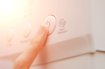 woman's finger presses the button to turn on the washing machine close up. Photo with illumination