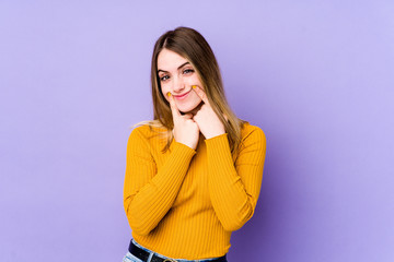 Young caucasian woman isolated on purple background doubting between two options.