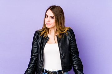 Young caucasian woman isolated on purple background shrugs shoulders and open eyes confused.