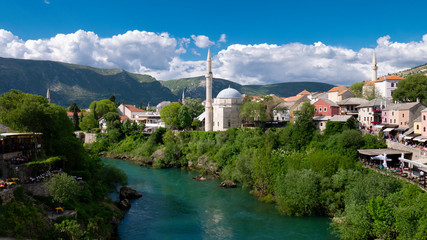 Fototapeta na wymiar Mostar / Bosnia and Herzegovina April 2019: Koski Mehmed Pasha Mosque in the center of shore of Neretva river in Mostar city