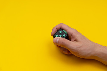 Antistress fidget in mans right hand on yellow background, close up, copy space - obrazy, fototapety, plakaty