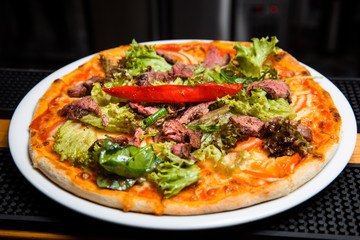 Pizza with meat and salad.