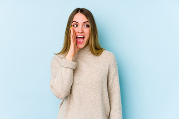 Young caucasian woman isolated on blue background shouting excited to front.