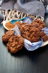 plate of cocoa cookies, brown cane sugar and chocolate, with blue tones on napkin, wooden table, tablecloth and spoon