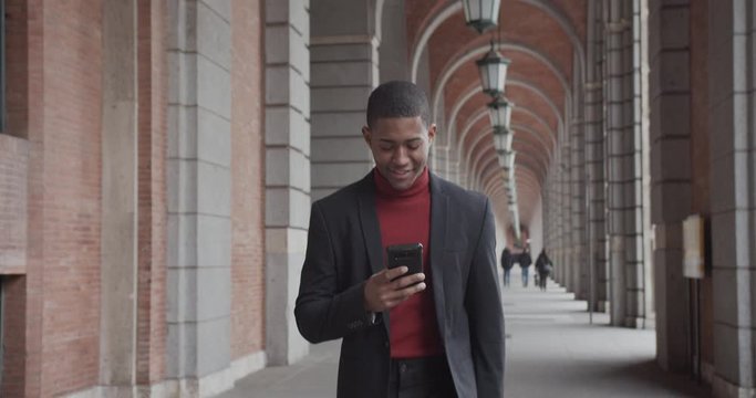 attractive black Hispanic young guy male businessman successful manager in a classic suit uses his smartphone
