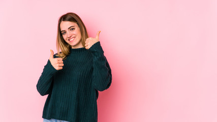 Naklejka premium Young caucasian woman isolated on pink background raising both thumbs up, smiling and confident.