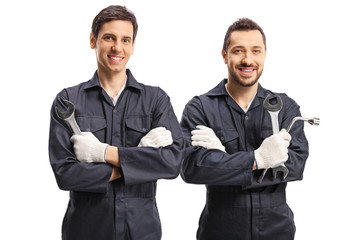 Two male workers in uniforms holding tools and looking at the camera