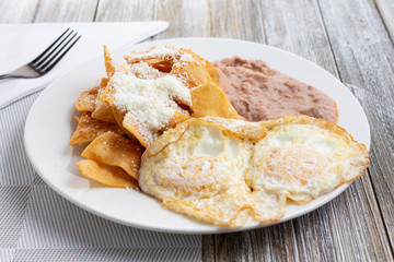 A view of a plate of huevos and chilaquiles, in a restaurant or kitchen setting.