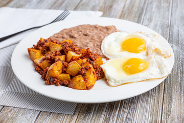 A view of a plate of potatoes and chorizo, in a restaurant or kitchen setting.