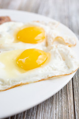 A closeup view of two sunny side up eggs or fried eggs in a restaurant or kitchen setting.