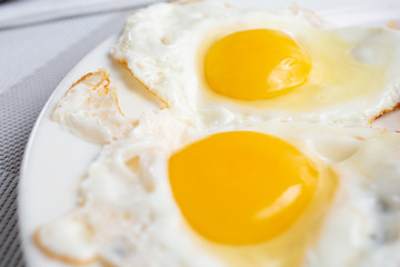 A closeup view of two sunny side up eggs or fried eggs in a restaurant or kitchen setting.