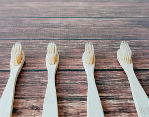A family set of four wooden toothbrushes on wooden background with copy space 