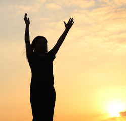 Fototapeta na wymiar woman silhouette arms up to the sunset feeling happy and freedom.