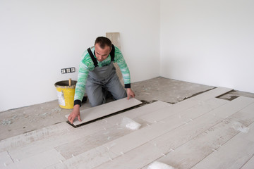 worker installing the ceramic wood effect tiles on the floor