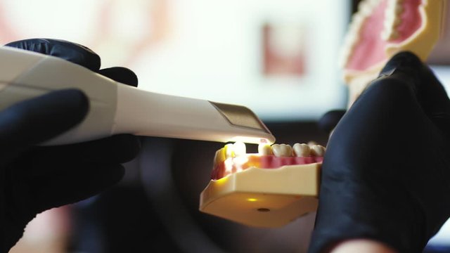 Close-up professional dental technician in science laboratory making new dental implants fake teeth removable jaw glazing zirconium. False teeth. Dental care.