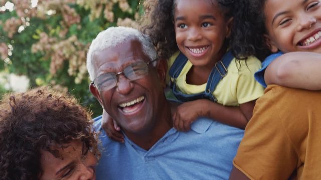 Portrait Of Multi-Generation African American Family Relaxing In Garden At Home Together 