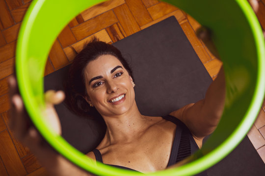 Young sporty woman doing toning pilates exercise with fitness circle, strength using pilates magic circle, wearing sportswear at yoga studio