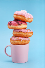 Sweet pink donuts with a pink mug on a blue background. Concept dessert, sweet life, we are what we...