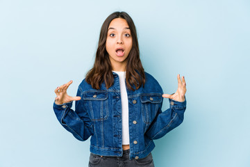 Young mixed race hispanic woman isolated holding something with palms, offering to camera.