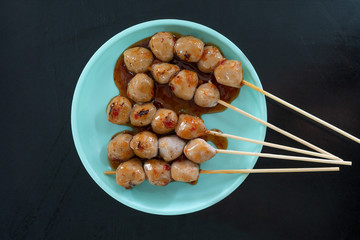 grill meat ball with sauce in the blue plastic plate on dark table