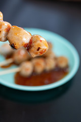grill meat ball with sauce in the blue plastic plate on dark table