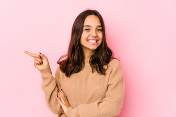 Young mixed race hispanic woman isolated smiling cheerfully pointing with forefinger away.