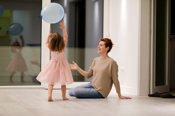 mother and cute little daughter playing with balloons