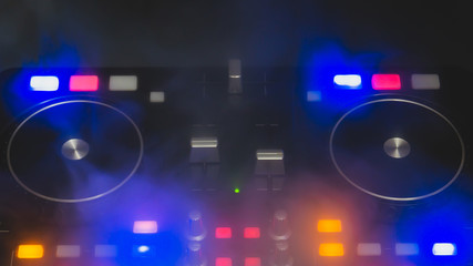 Dj sound mixer controller with knobs and sliders. audio mixing deck with turntables at dark with illuminated controls