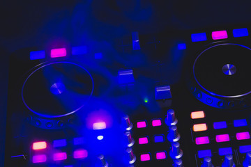 Dj sound mixer controller with knobs and sliders. audio mixing deck with turntables at dark with...