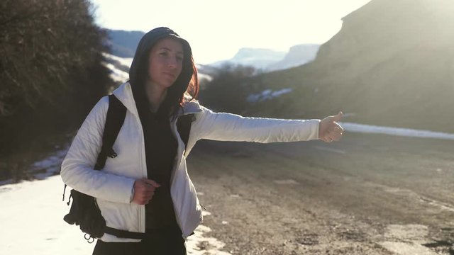 Tourist girl with a large backpack hitchhiking on a lonely rural road. Journey autostopem alone.