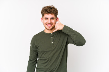 Obraz premium Young blond curly hair caucasian man isolated showing a mobile phone call gesture with fingers.