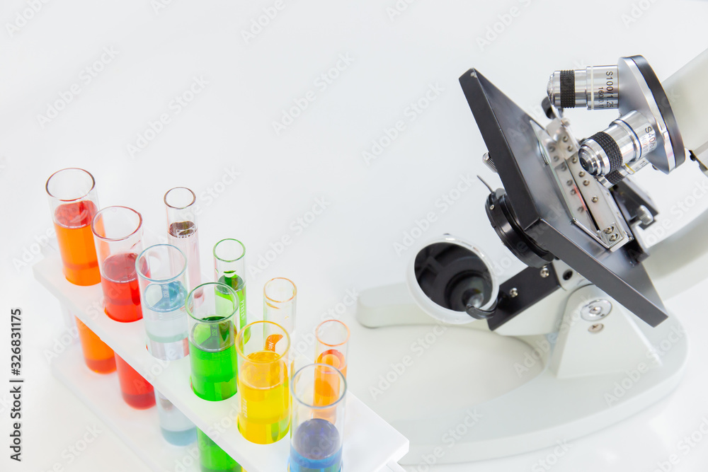Poster Test tubes in a stand and a microscope on a white table